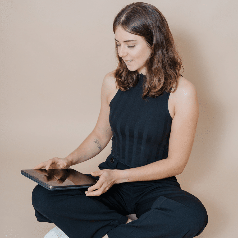 Marlene-König-Kleinl in schwarzem Outfit mir weißem Sessel, Laptop und Ipad.